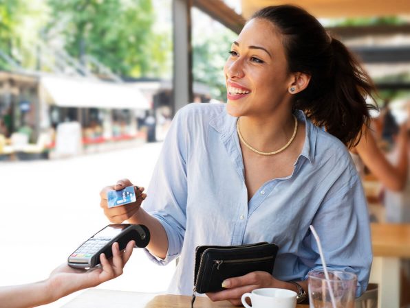 woman smiling while using contactless payment to pay for her meal